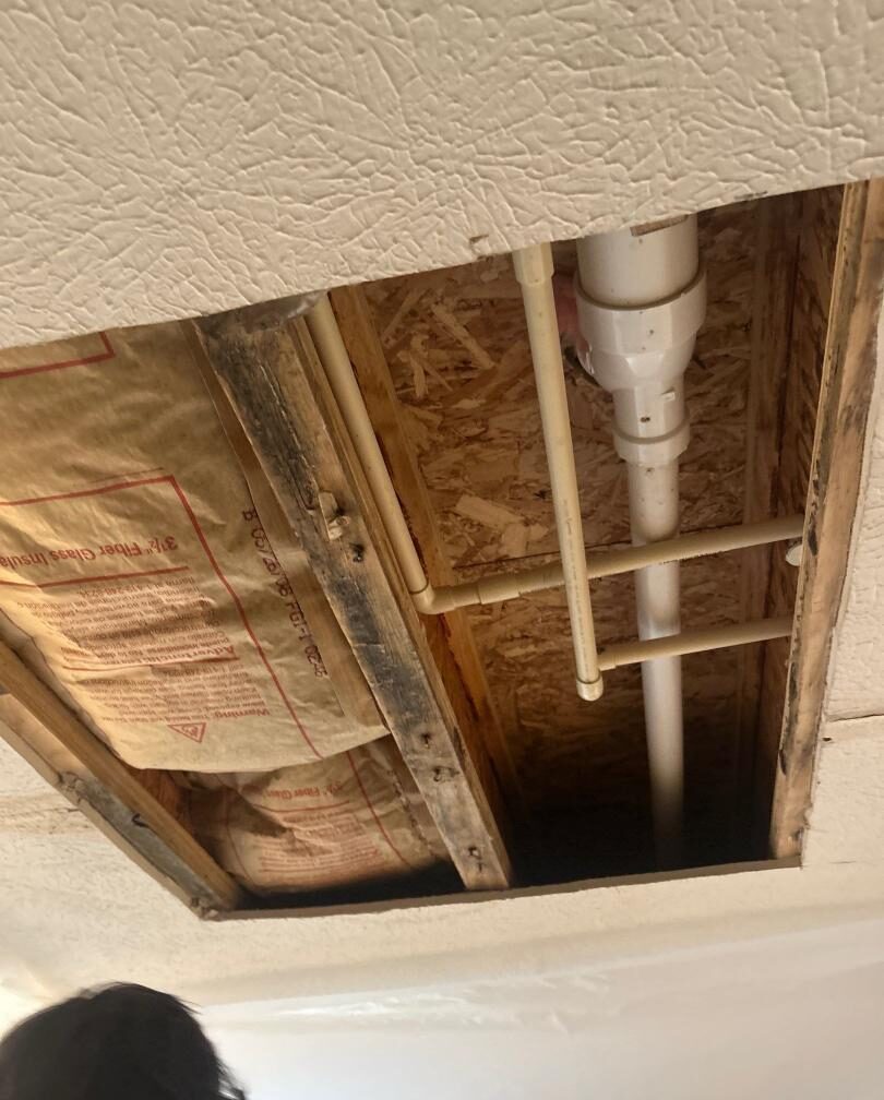 Ceiling with exposed wooden beams and plumbing pipes.