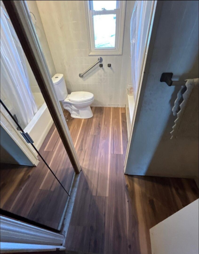 Bathroom with new dark wood-look flooring and finished walls