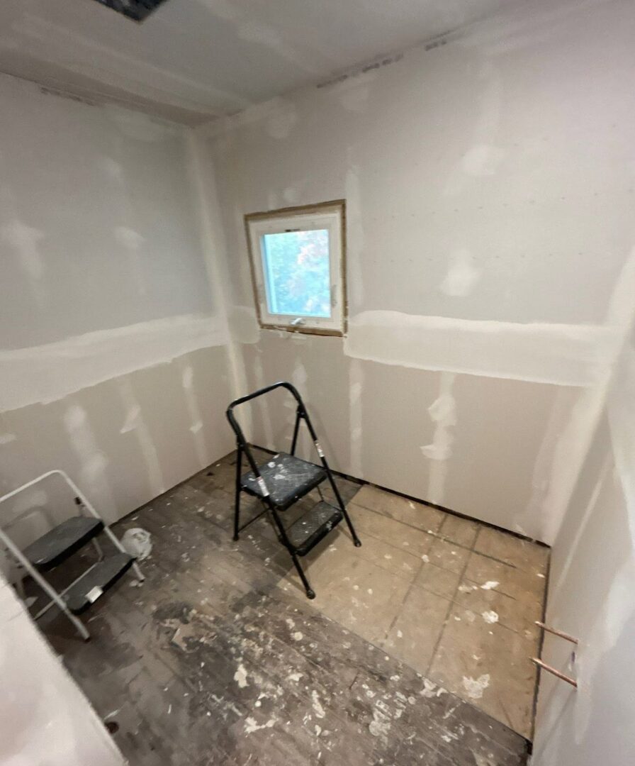Small room at the drywall patch-and-tape stage with step ladders