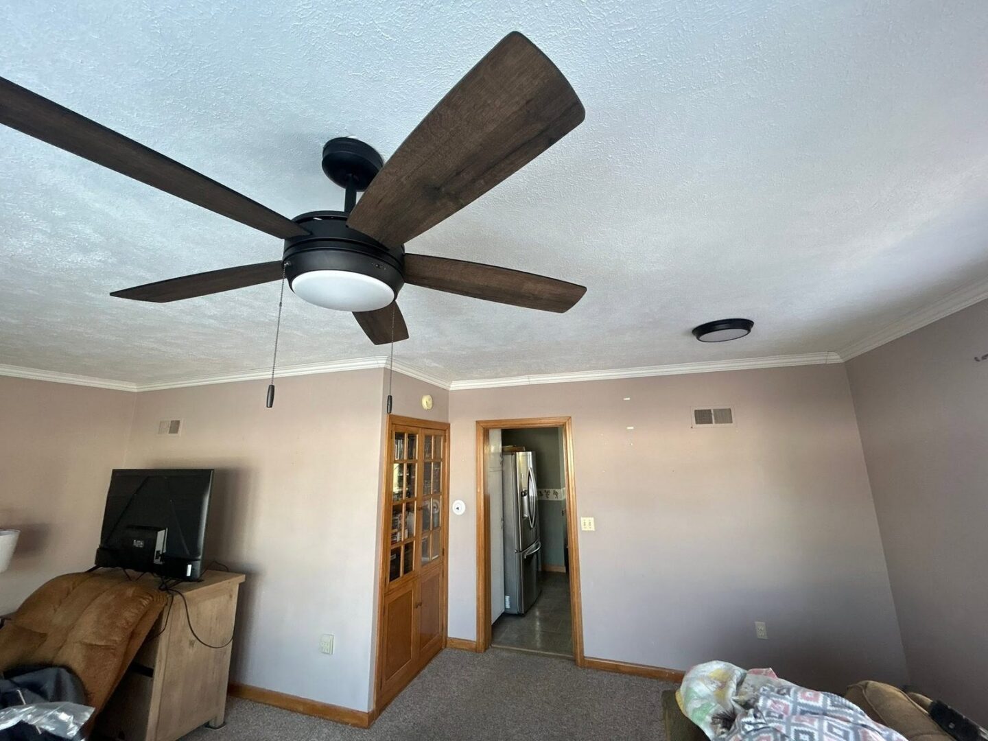 Finished living room with new drywall and a ceiling fan