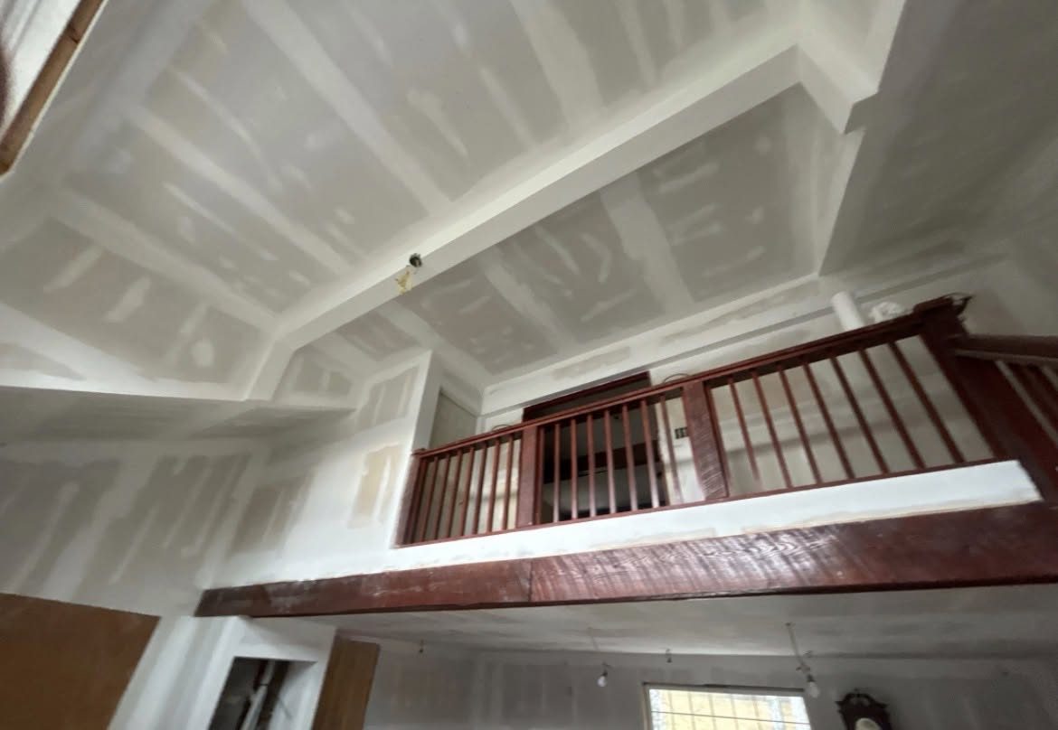 Two-story room with finished drywall and a red loft railing