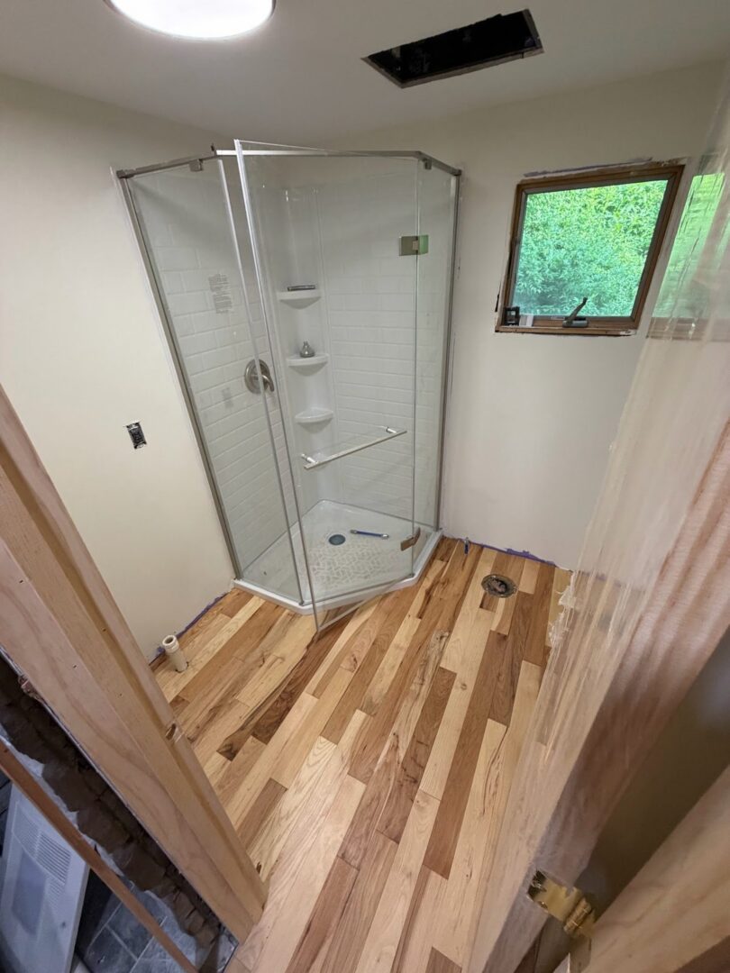 Remodeled bathroom with a glass corner shower and wood-look flooring