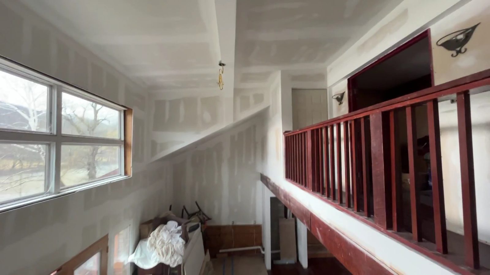 Upper-level room with a red railing and a row of windows